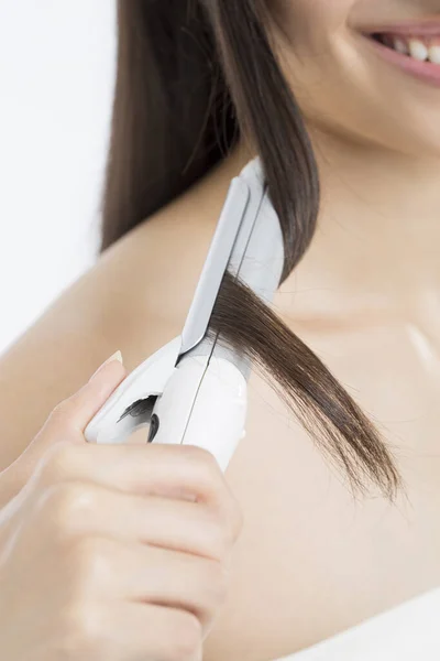 Beautiful   woman curling long hair using curling iron.