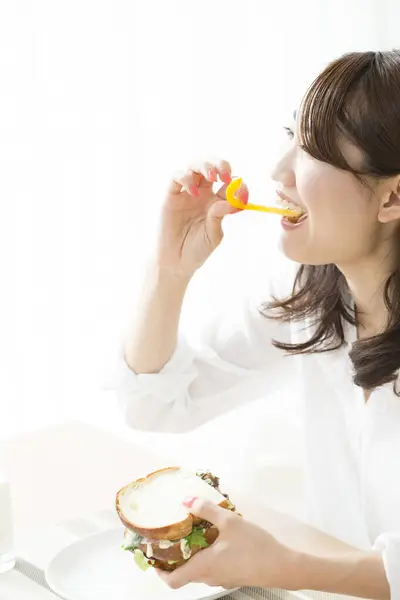 おいしいサンドイッチを食べる若いアジアの女性 — ストック写真