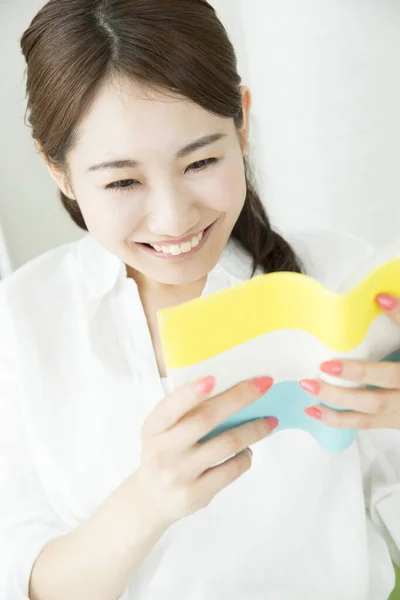 Glimlachende Aziatische Vrouw Lezen Boek Thuis — Stockfoto