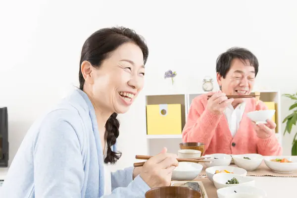キッチンで食事を持っているシニアアアジアのカップル — ストック写真