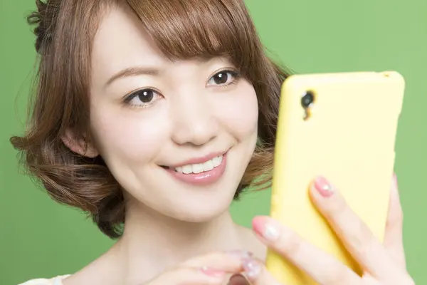 Yeşil Arka Planda Akıllı Telefon Kullanan Güzel Bir Japon Kadının — Stok fotoğraf