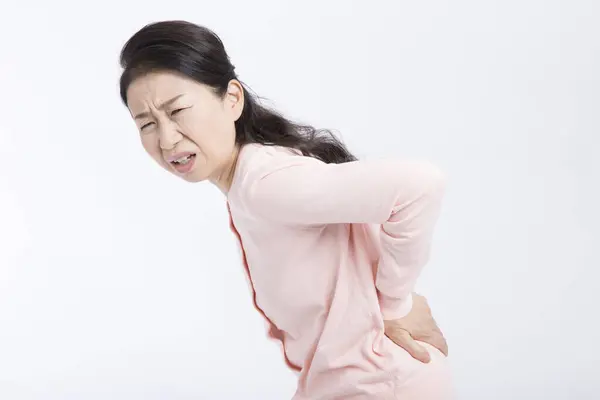 白种人背景的亚裔老年妇女背痛 — 图库照片