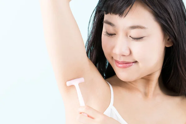 young woman shaving  armpit to remove hair