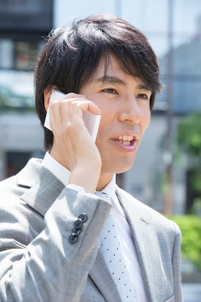 英俊的亚洲专业商人在街上用电话交谈 — 图库照片
