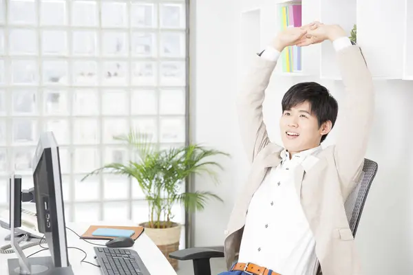 asian businessman in a modern office stretching
