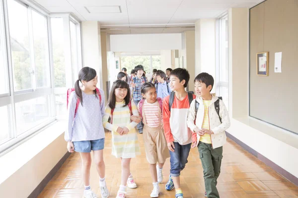 Grupa Japońskich Dzieci Plecakami Spacerujących Korytarzu Szkolnym — Zdjęcie stockowe