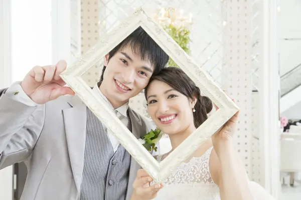 美しい若い結婚式のカップルの肖像画は優雅な装飾的なフレームを通してカメラで微笑みます — ストック写真