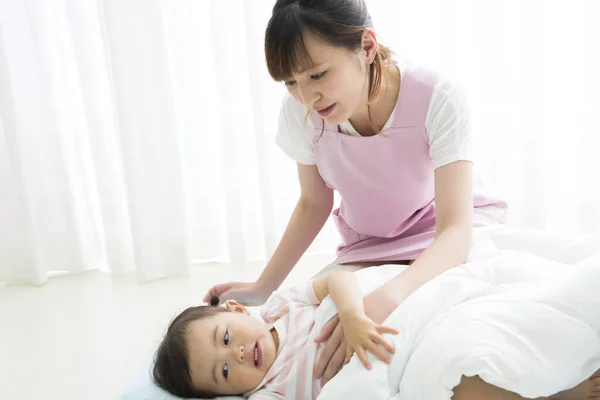 Asiatico Giovane Scuola Materna Insegnante Mettendo Ragazza Dormire Foto Stock