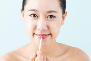 Genç, güzel Asyalı kadın dudak parlatıcısı sürüyor.