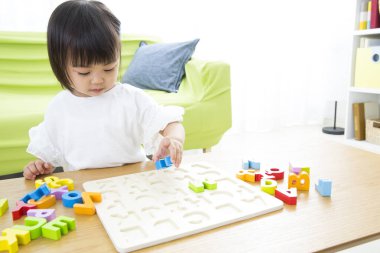 Küçük çocuk anaokulunda renkli plastik harflerle oynuyor..