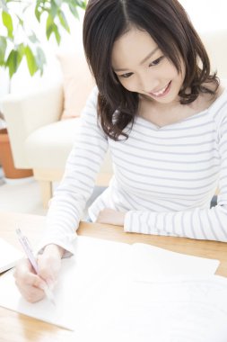 Genç Asyalı öğrenci not defterine yazıyor.