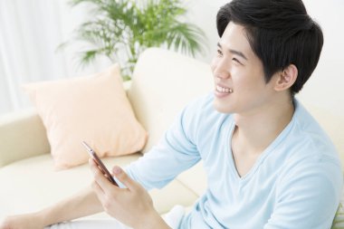 Adam evde dinlenirken akıllı telefon kullanıyor.