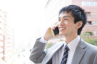 Cep telefonu olan ve sokakta gülümseyen bir işadamı. 