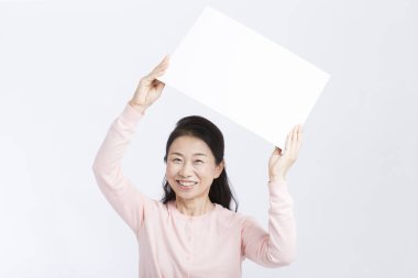 Beyaz arka planda boş pankart taşıyan yaşlı Asyalı kadın. 