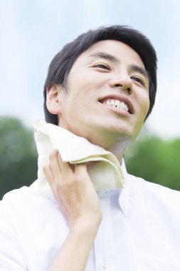 Sıcak yaz parkında havluyla genç Asyalı adamın portresi.