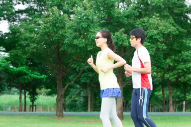 Sportif genç Asyalı çift parkta koşuyor.