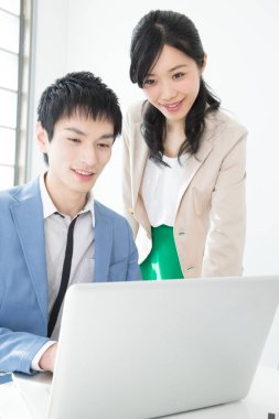 Genç iş adamı ve kadın ofiste dizüstü bilgisayarda çalışıyor.