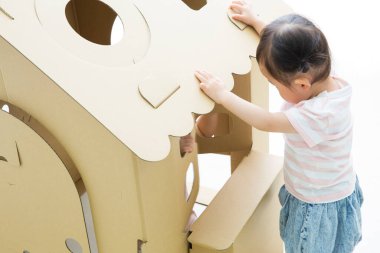 Küçük tatlı Asyalı kız odada oyuncak eviyle oynuyor.