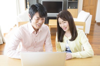 Evde dizüstü bilgisayarda çalışan Asyalı çift.