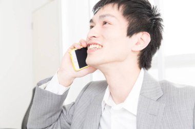 Ofiste telefonla konuşan genç Japon iş adamının yakın plan portresi.