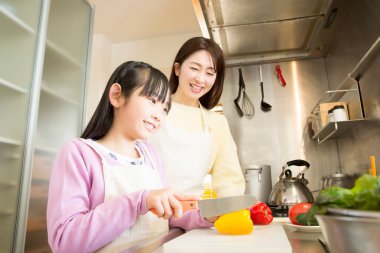 Genç anne ve kız mutfakta taze salata hazırlıyorlar. 