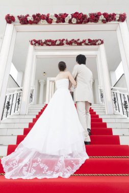 Merdivenlerde kırmızı halıyla yürüyen genç ve güzel bir çiftin arka manzarası. 