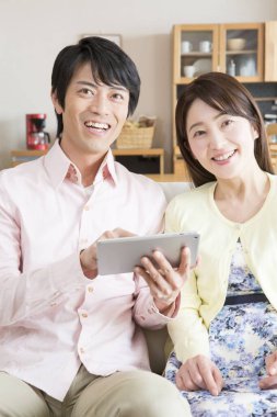Asyalı genç çift evde tablet bilgisayar kullanıyor. 