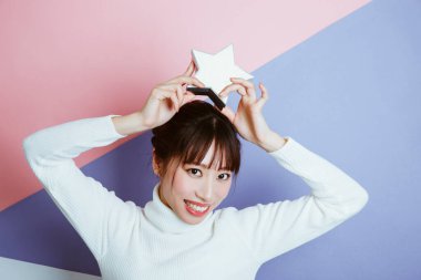 Kafasında bir noel yıldızı tutan gülümseyen Asyalı bir kadının portresi