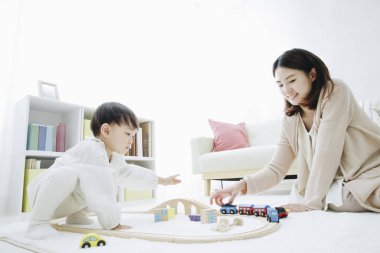 Genç Asyalı anne ve oğlu oyuncak trenle oynuyorlar.