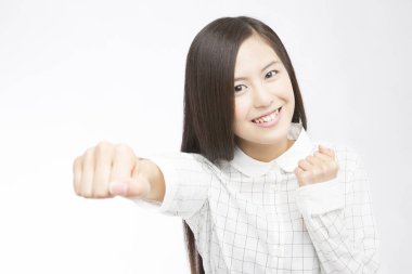 Beyaz arka planda yumruklarını gösteren güzel bir Japon kadının stüdyo fotoğrafı. 