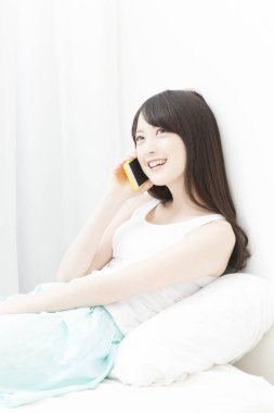 Yatağa akıllı telefon kullanan kadın 