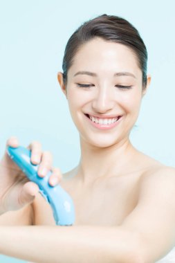 Elektrikli epilatör kullanan güzel Asyalı kadın.