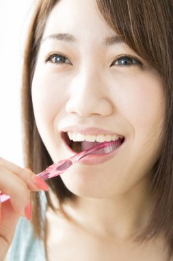 Genç bir Asyalı kadın dişlerini fırçalıyor.