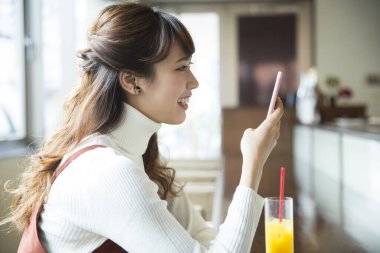 Restoranda cep telefonu olan genç bir kadın.