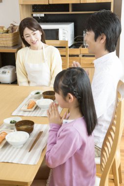 Mutlu Asyalı bir aile mutfakta kahvaltı yapıyor.