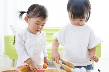 Küçük kız, kız kardeşine mutfakta yardım ediyor.