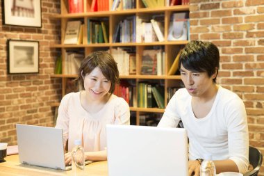 Masada dizüstü bilgisayar kullanan Asyalı çift.