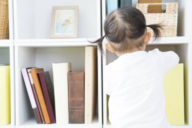 Küçük çocuk kitaptan kitap alıyor. 