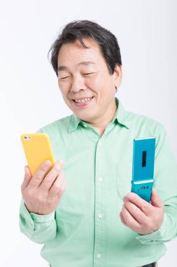 Cep telefonu ve akıllı telefon tutan usta Asyalı adam, stüdyo fotoğrafı.