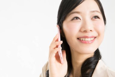 Beyaz arka planda akıllı telefondan konuşan güzel Japon kadının portresi. 