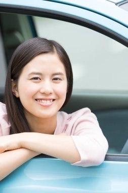 Genç Asyalı kadın yeni arabasında oturuyor.