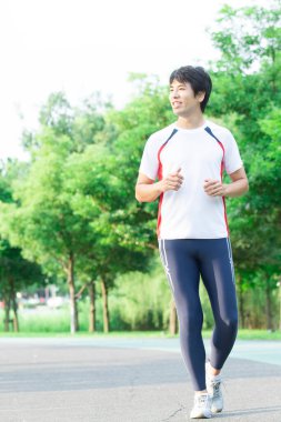 Genç yakışıklı Asyalı adam parkta koşuyor. 