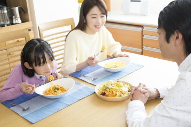 Aile yemek masasında yemek yiyor.