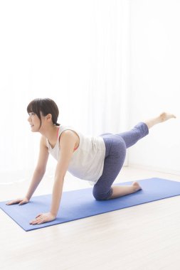 Evde yoga yapan genç bir kadın.