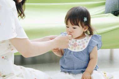 Asyalı anne kızını besliyor.