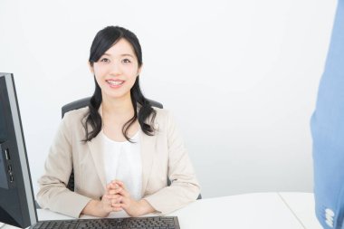 Ofisinde bilgisayarı olan Asyalı genç bir iş kadını.