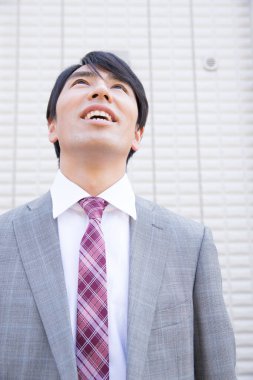 Takım elbiseli genç Japon işadamı evden ayrılıyor.