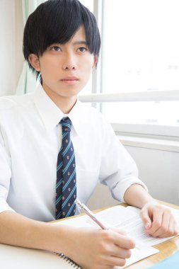 Genç adam pencerenin yanındaki masada çalışıyor.