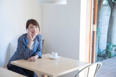 Akıllı telefonlu bir kadın masada oturuyor. 