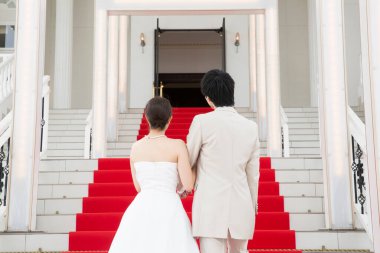 Merdivenlerde kırmızı halıyla yürüyen genç ve güzel bir çiftin arka manzarası. 